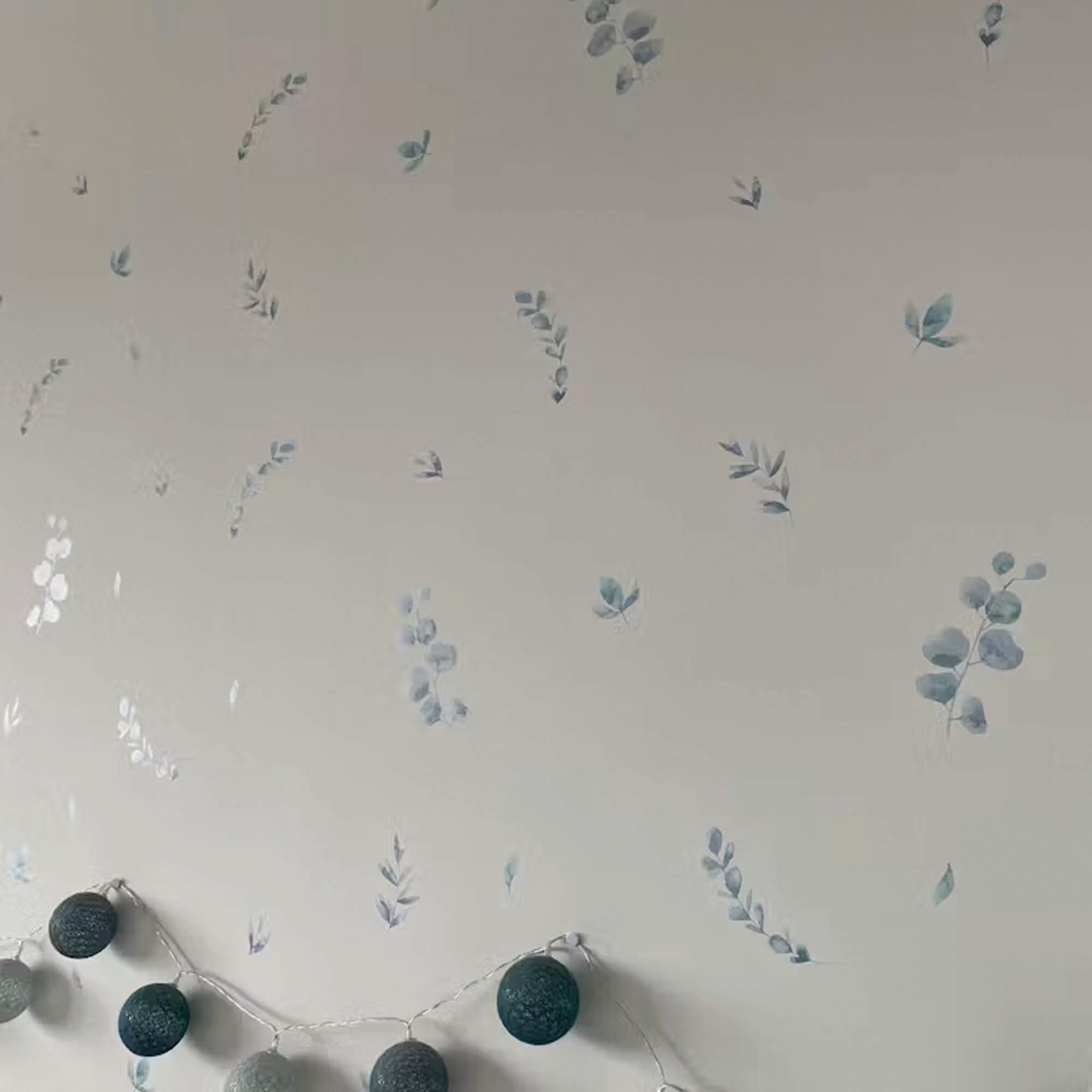 Primer plano del vinilo decorativo pra paredes en forma de plantas de eucalipto en color verde sobre la pared blanca de un dormitorio - Nicolasito.es #color_plantas-eucalipto-verde