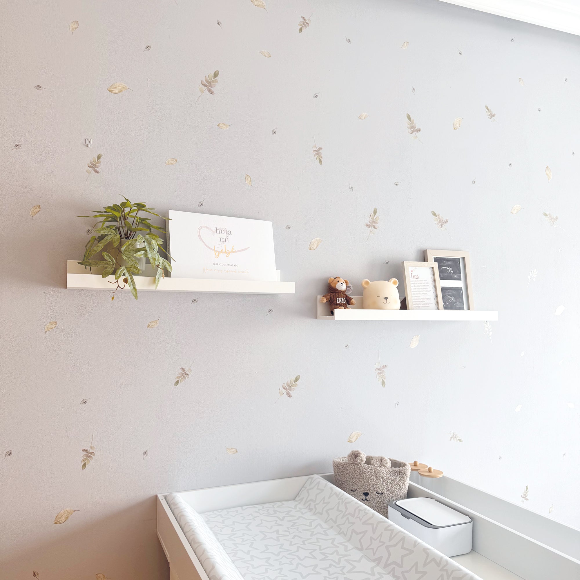 Plano detalle de pared de dormitorio de bebé con paredes decoradas con vinilo decorativo adhesivo en forma de hojas con acabado acuarela. Vinilo adhesivo de paredes de alta calidad y resistente - Nicolasito.es