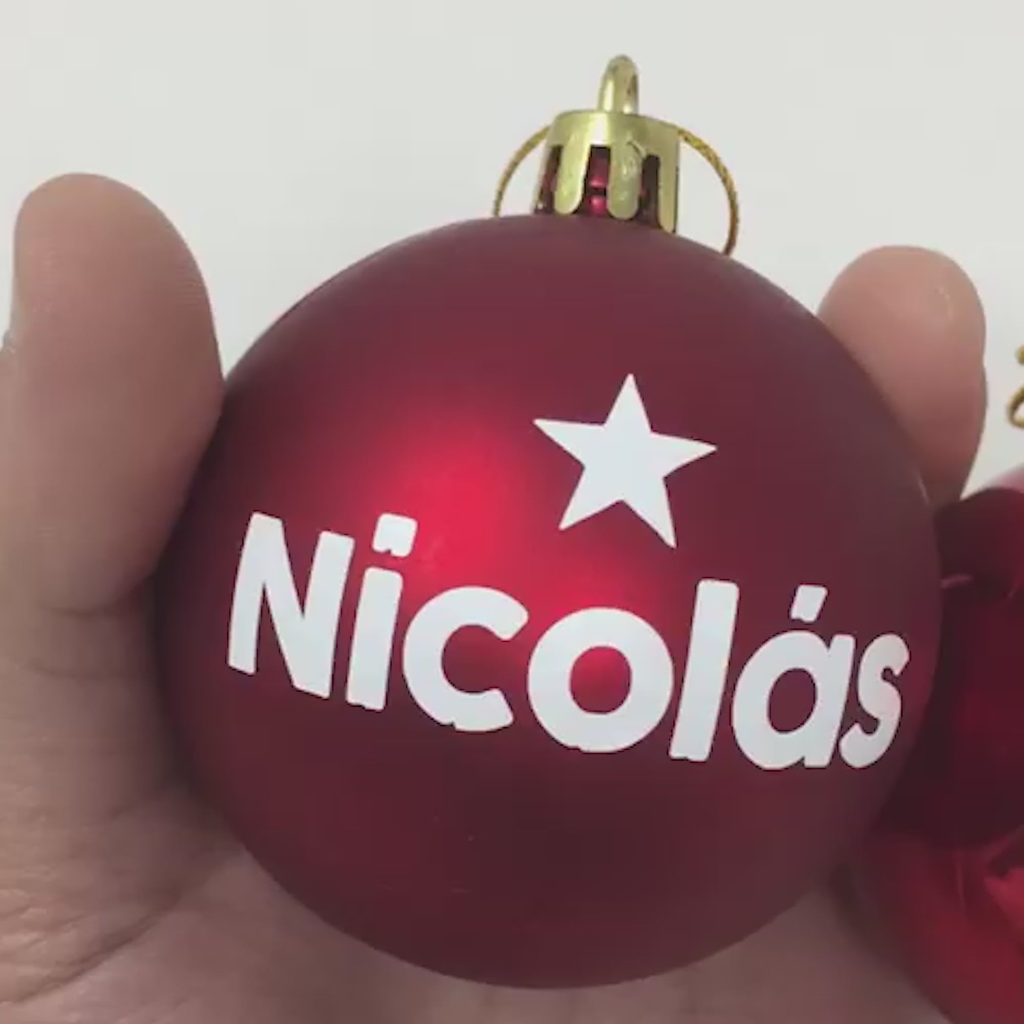 Vídeo de bola de Navidad personalizada con nombre mostrando los acabados brillo y mate, perfecta para decorar el árbol navideño o regalar en Navidad. Hecha con materiales de calidad y personalización artesanal, ideal como detalle para familia y amigos - Nicolasito.es