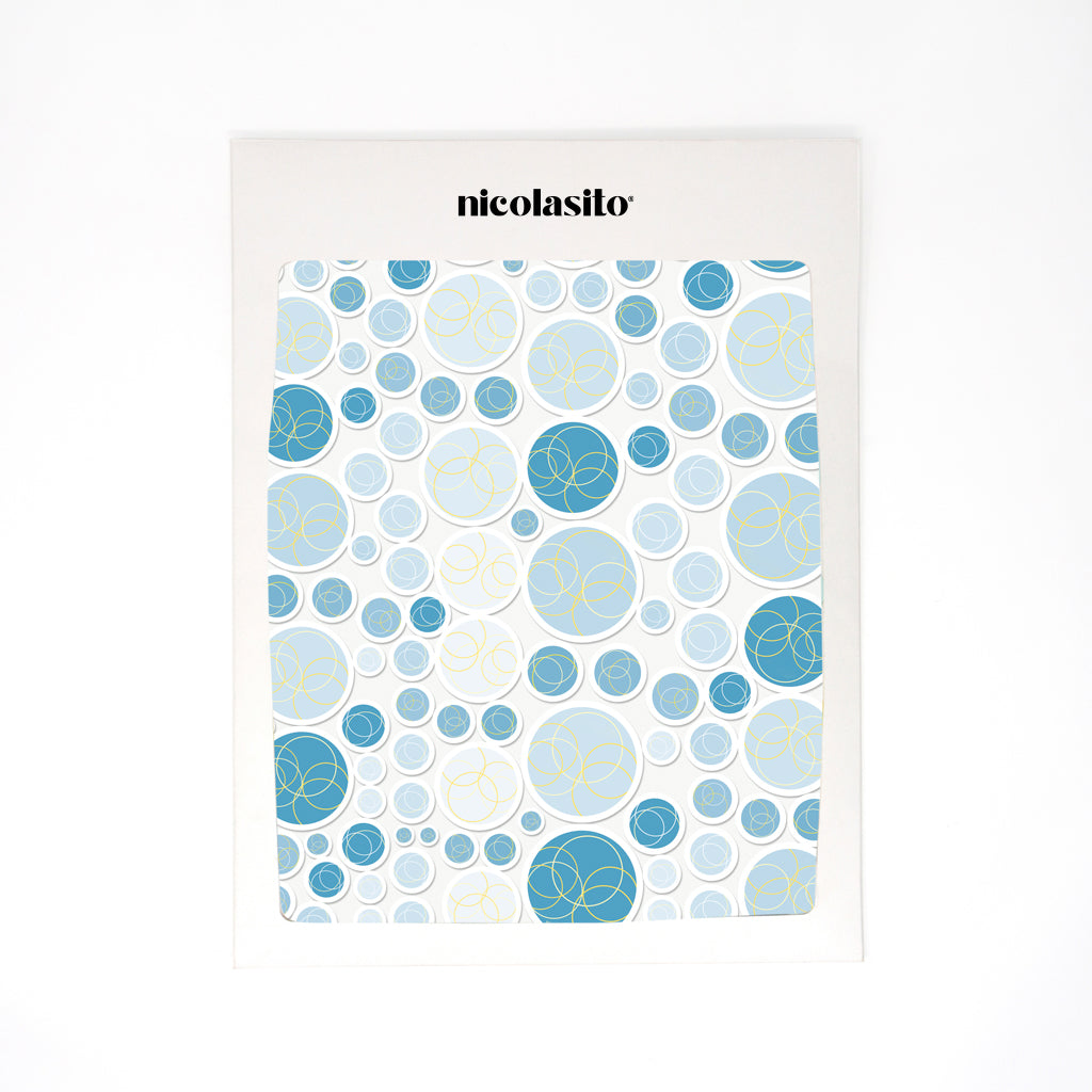Imagen de las 90 pegatinas de burbujas azules organizadas sobre un sobre de packaging, mostrando la variedad de tamaños y tonos - Nicolasito.es #color_Azul