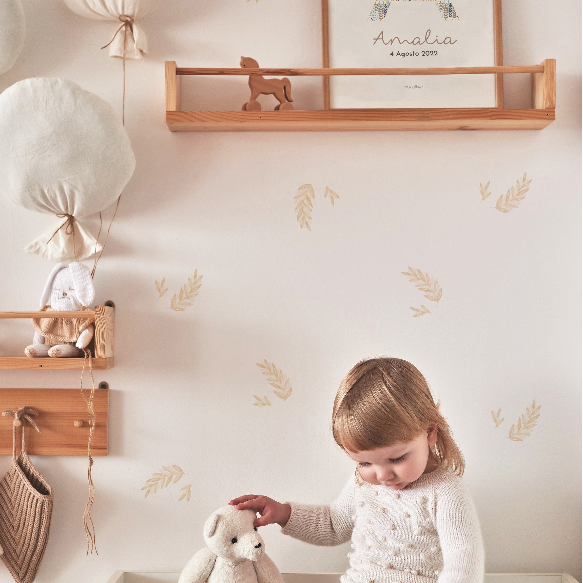 Imagen en la que se ve a una niña jugando en su dormitorio en tonos tierra y con muebles de madera y vinilos decorativos en forma de plantas laurel en color beige sobre las paredes del dormitorio - Nicoalsito.es #color_Plantas-Laurel-Beige