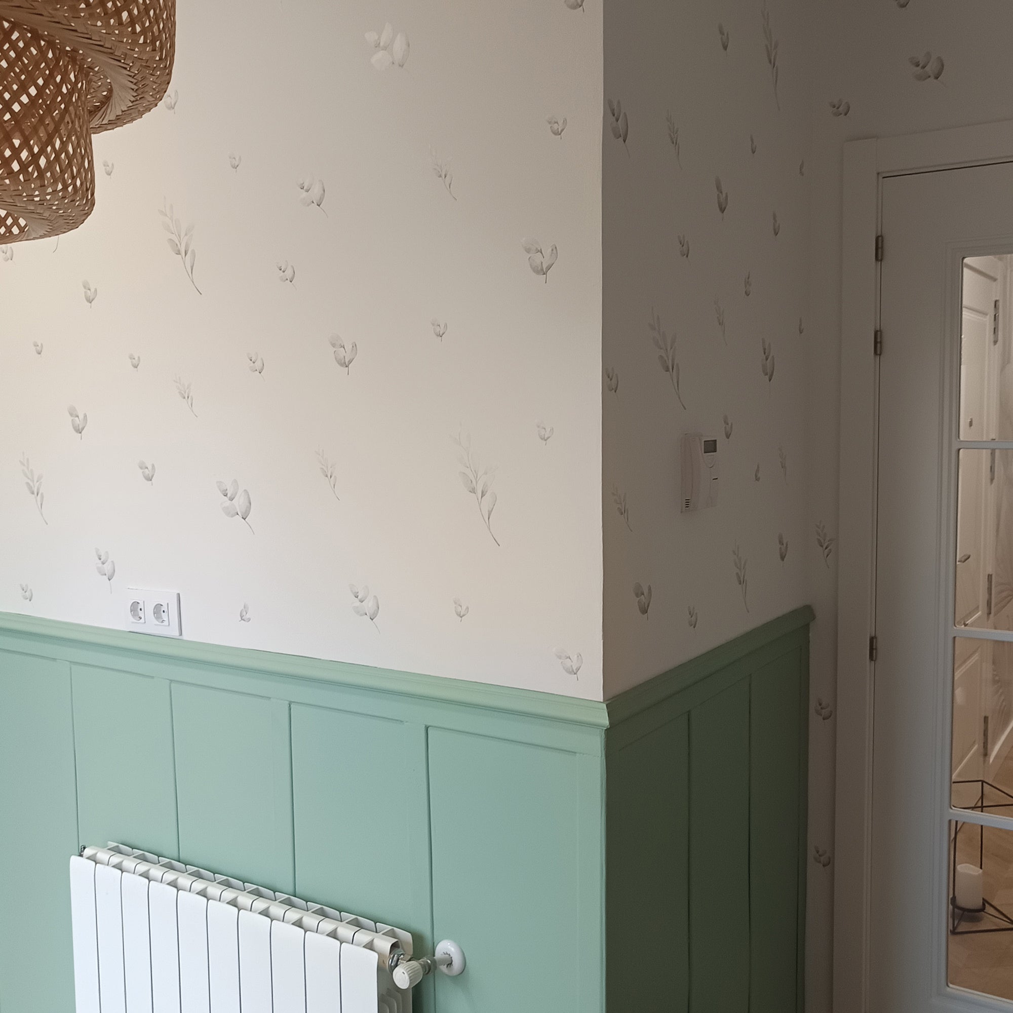 Plano detalle de las paredes de una cocina minimalista decoradas con vinilo decorativo de paredes en forma de hojas y ramas de color verde con acabado acuarela y de varios tamaños #tamaño_Pequeño
