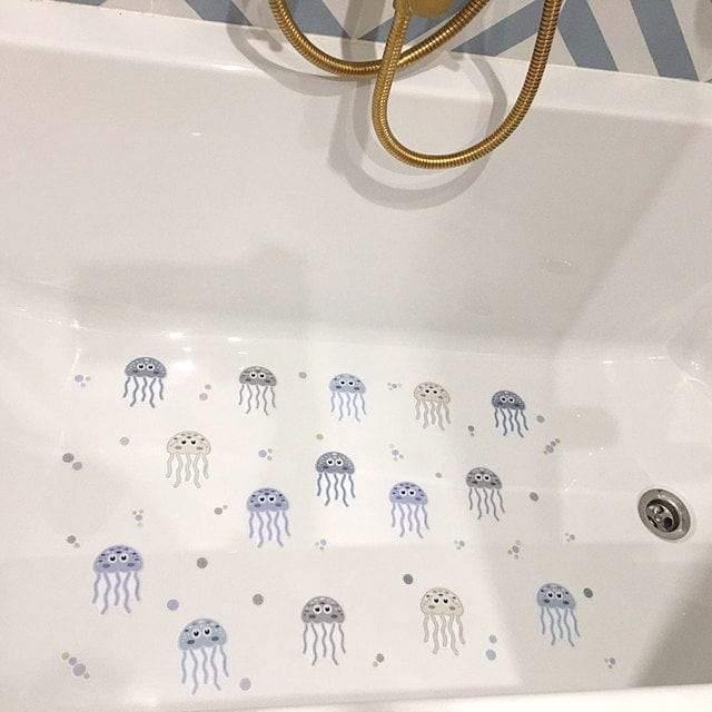 Bañera blanca lujosa con detalles dorados decorada con 15 pegatinas antideslizantes de medusas en tonos azules y lilas, distribuidas uniformemente sobre el fondo blanco para seguridad durante el baño - Nicolasito.es #color_Azul