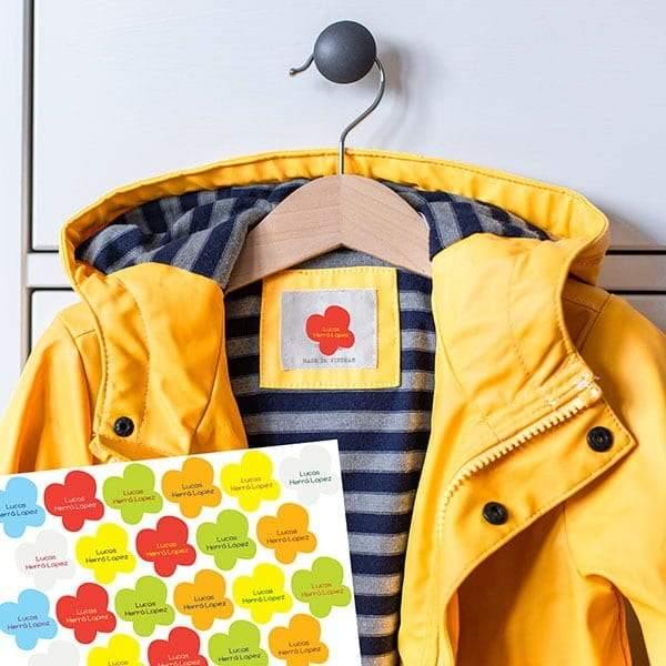 Plano detalle de las etiquetas termoadhesivas y personalizables en forma de mariposas de diferentes colores sobre un chubasquero amarillo infantil. Etiquetas personalziadas ideales para marcar toda la ropa y resistentes al lavado - Nicoaslito.es #color_Multicolor