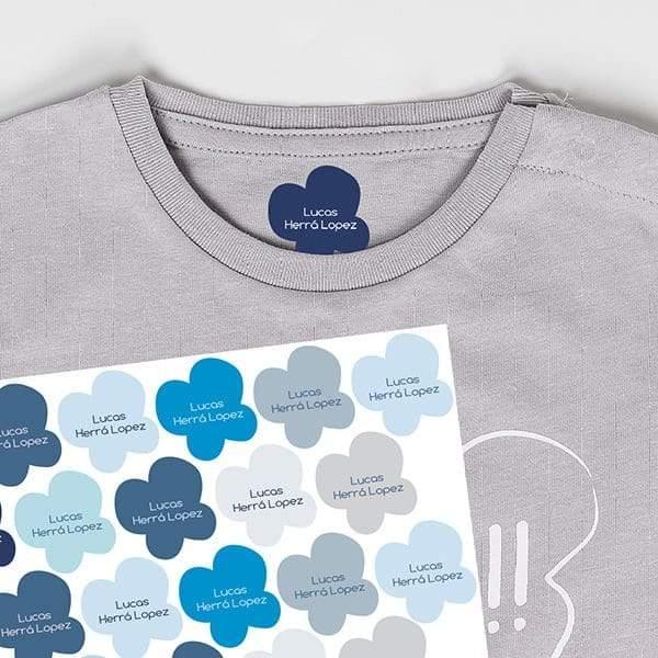 Etiquetas termoadhesivas con diseño de mariposas de color azul colocadas sobre una camiseta gris de algodón, perfectas para identificar toda la ropa en cuestión de sgundos; cuentan con un adhesivo fuerte y duradero - Nicolasito.es #color_Azul