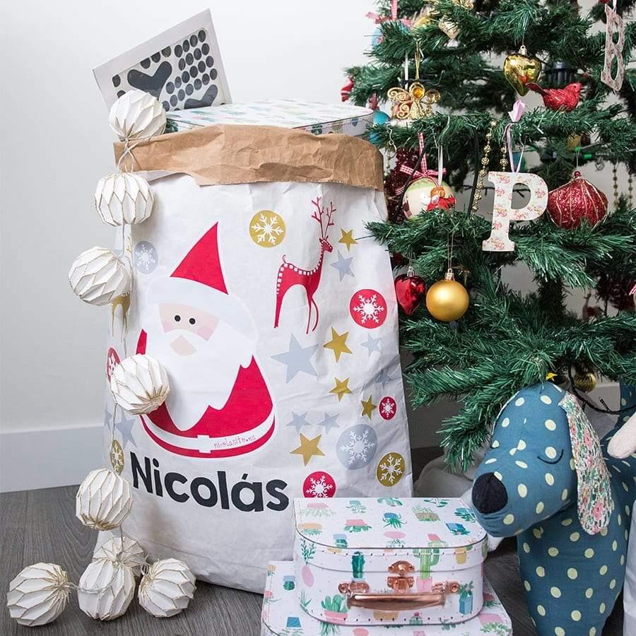 Saco de papel de Papá Noel personalizado con nombre colocado bajo el árbol de Navidad, decoración navideña sostenible para guardar regalos - Nicolasito.es