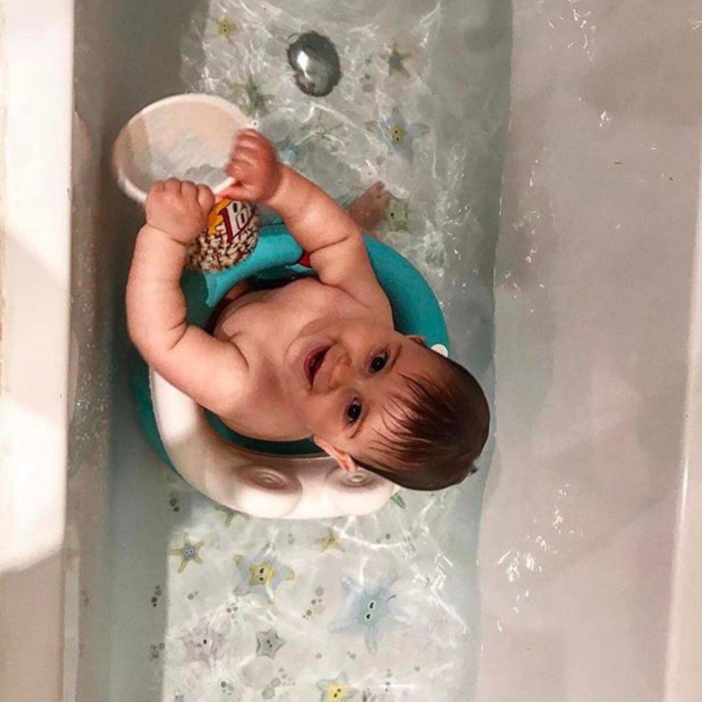 Imagen de una niño sonriente y jugando dentro de una bañera llena de agua sobre la que se colocan pegatinas antideslizantes en forma de estrellas de mar de color verde y creando un ambiente seguro y dirvertido sin resbalones durante el baño. - Nicolasito.es #color_Verde