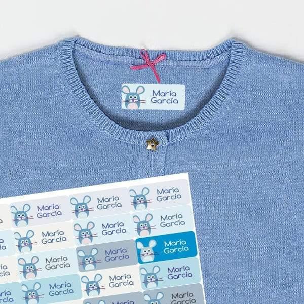 Plano detalle de las etiquetas termoadhesiva para ropa con diseño de ratones de color azul y nombre personalizado en tipografía legible, sobre una chaqueta infantil de punto azul. Etiquetas ideales para identificar prendas escolares y soportar el uso diario - Nicolasito.es #color_Azul