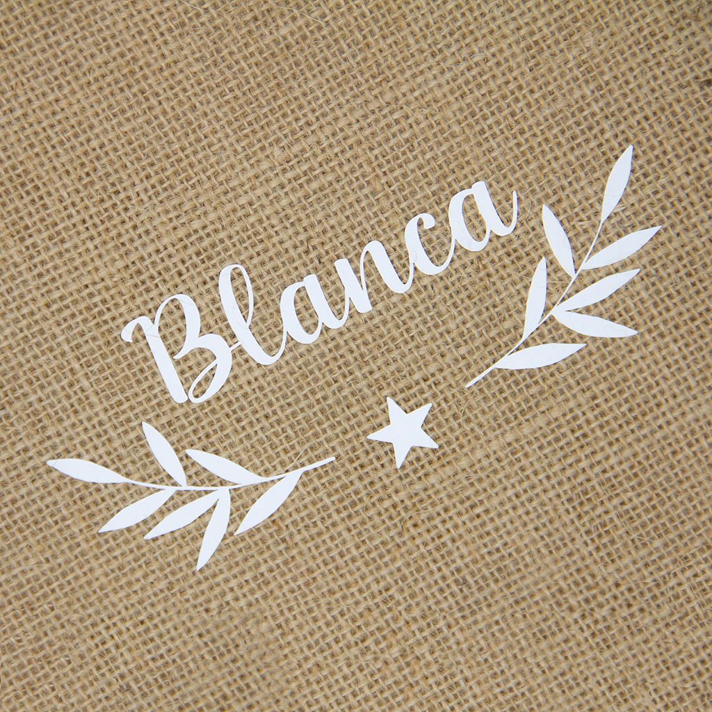 Detalle del nombre personalizado en vinilo sobre saco de Navidad de yute blanco, regalo navideño artesanal y sostenible - Nicolasito.es #color_Blanco