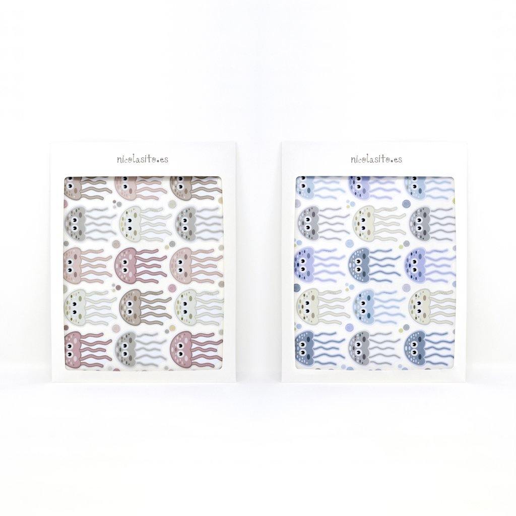 Conjunto de 15 pegatinas de medusas organizadas sobre una superficie plana, destacando su diseño colorido, rosa o azul y tamaño uniforme - Nicoasito.es