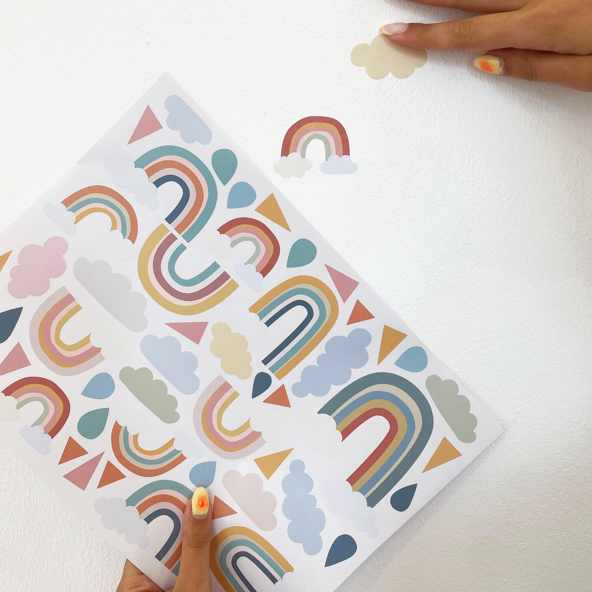 Video colocación vinilo decorativo para paredes en forma de arcoiris y nubes sobre pared de dormitorio infantil - Nicoalsito.es