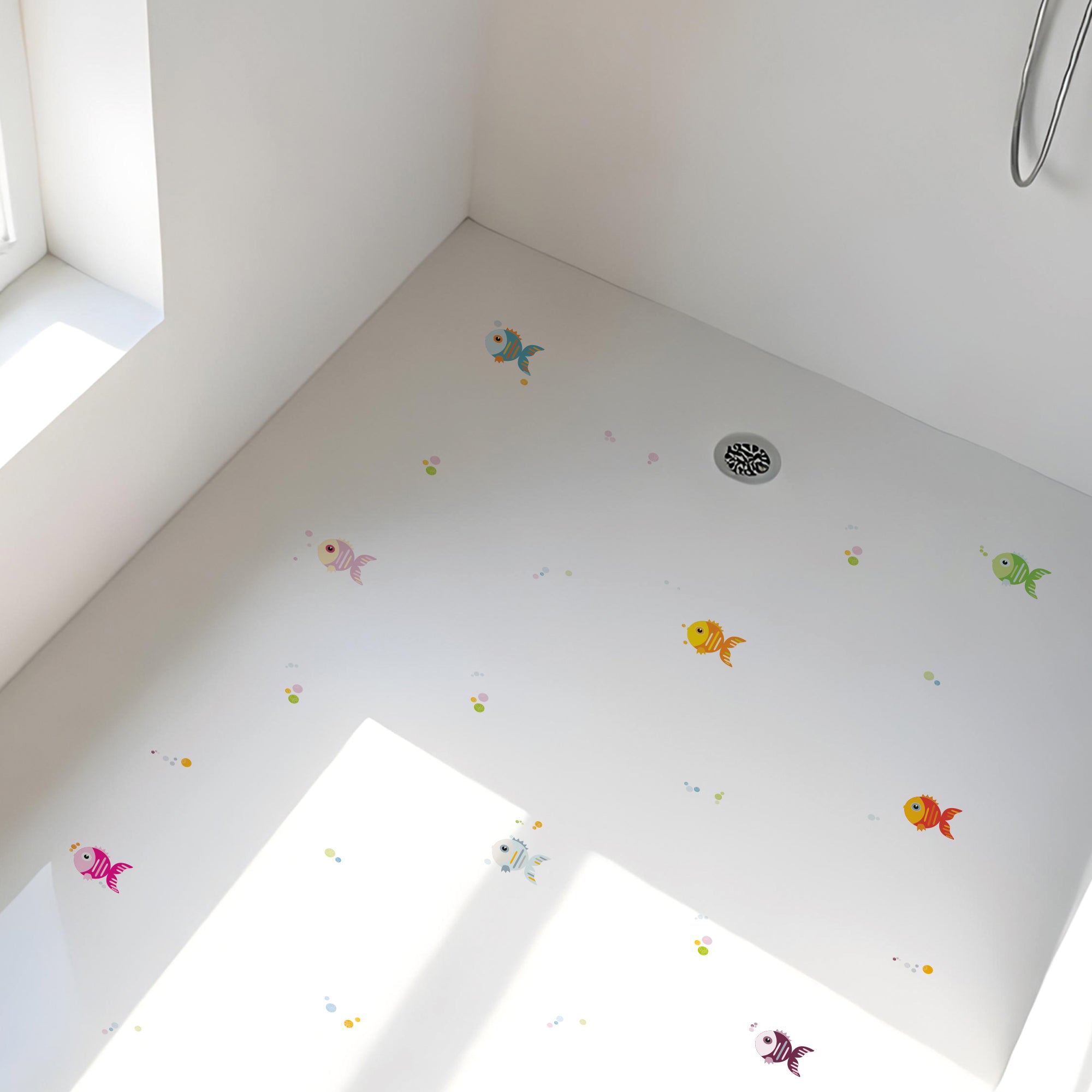 Vista detallada de plato de ducha minimalista con pegatinas antideslizantes infantiles en forma de peces de colores y burbujas para evitar resbalones en el baño - Nicolasito.es